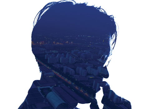 A double exposure of a man and the city lights.