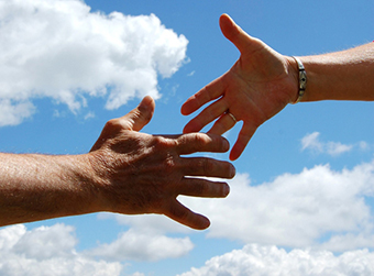 Two hands reaching out to each other in the sky.